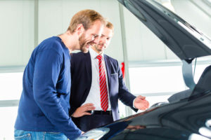 Seller or car salesman and client or customer in car dealership